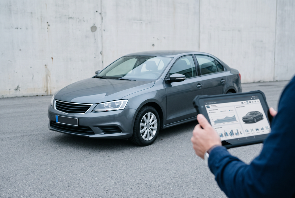 Sachverständiger dokumentiert einen Pkw mit einem Tablet